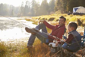 Father and son fishing by a lake, dad looks to camera