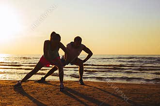 Fitness couple stretching in sunset