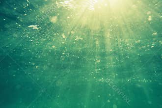 Underwater shot with sunrays and bubbles in deep tropical sea