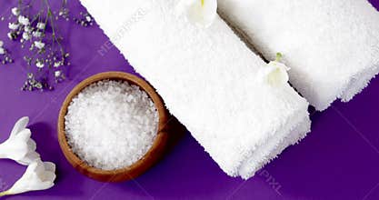 Sea salt in wooden bowl, towel and flowers