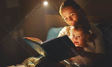 Mother and child girl reading a book in bed