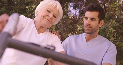 Male nurse assisting a senior woman to walk in the backyard