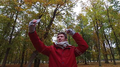 Man with smartphone taking video at autumn park