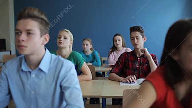 Students with notebooks writing test at school
