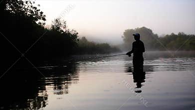 Fisherman goes fly fishing in the morning river