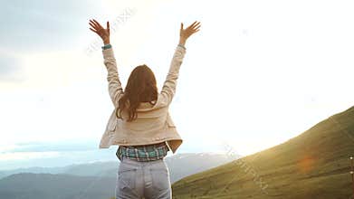 Happy celebrating winning success woman at sunset or sunrise standing elated with arms raised up above her head in