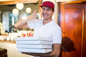 Pizza delivery man holding pizza boxes making a phone gesture