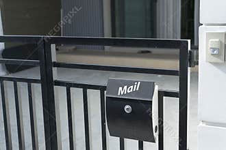 Modern mail box on house fence