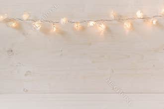 Christmas lights burning on a white wooden background.