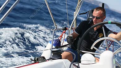 Skipper at the helm controls of a sailing yacht during race