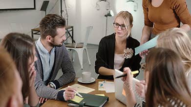 Creative business team at the table in a modern startup office. Female leader explains the details of the project.
