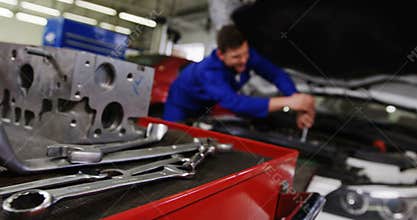 Car parts with tools and mechanic working in background