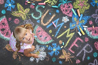 Child drawing summer spirit on asphalt