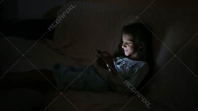 Little girl using a cell phone at night