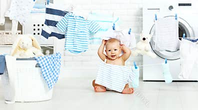 Fun happy baby boy to wash clothes and laughs in laundry