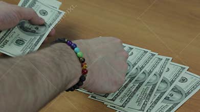 Men`s hands with a bracelet count the bills