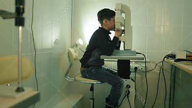 Boy checks eye vision in ophthalmology clinic - wide angle