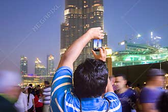 A man in the crowd photographs the Dubai skyline