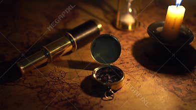 Compass and spyglass on old world map in candlelight