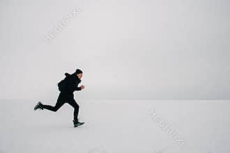 A young man in a black backpack and traveling on the frozen pond