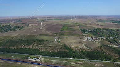 Aerial flight above green meadows and windmills