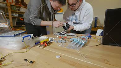 Engineers in laboratory discuss robotic bionic arm made on 3D printer.