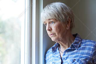 Senior Woman Suffering From Depression Looking Out Of Window