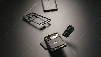 SLOW MOTION: Smartphone falls on a floor, breaks and a parts fly away