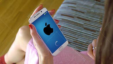 Young woman holding a cell phone with loading Apple mobile app. Conceptual editorial 4K clip