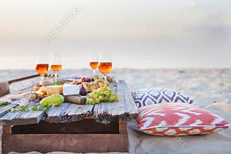 Picnic on the beach at sunset in boho style, food and drink conc