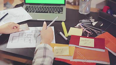Top view of the hands of the designer reformating the data on the location of furniture in the new apartment