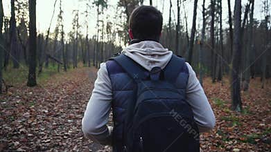 Adult man walks along the autumnal forest to get new impressions of nature.