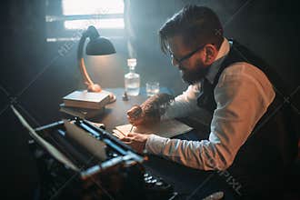 Writer in glasses writes novel with a feather