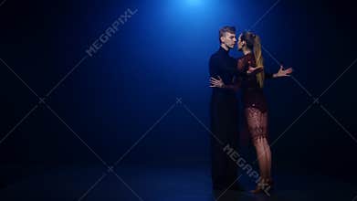 Tango dancing couple of professional elegant dancers in smoky studio