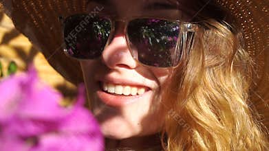 Lady in straw hat and sunglasses smiling on camera