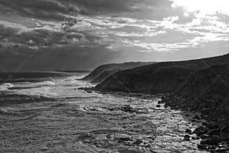 Stormy sea at rocky coast black-and-white