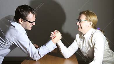 Businesswoman and businessman arm wrestling at the office, Man and woman