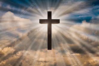 Jesus Christ cross on a sky with dramatic light, clouds, sunbeams. Easter, resurrection, risen Jesus concept