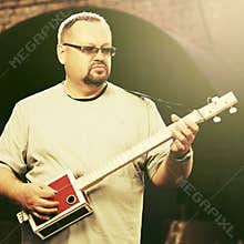 Handsome man playing his cigar box guitar