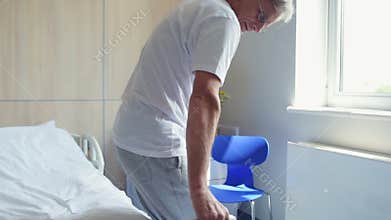 Senior disabled man walking on the crutches in the hospital