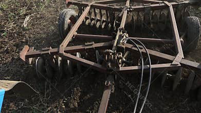 Closeup of plow attached to a tractor plowing a field.