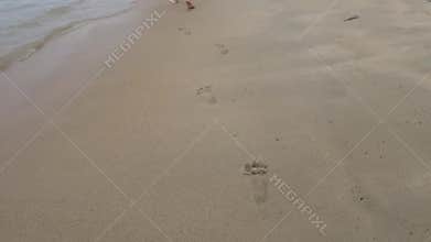 Steps baby on the beach barefoot.