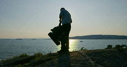 Active man with backpack camping at the moutain by the sea at sunset