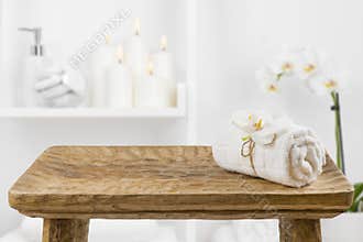 Wooden table with spa towel on blurred bathroom shelf background