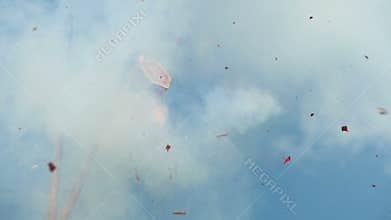 Red firecracker explodes against blue sky