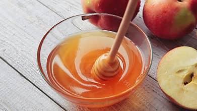 Movie of honey dripping. Apples on wooden table. Traditional celebration food for the Jewish New Year. Concept Rosh Hashana.