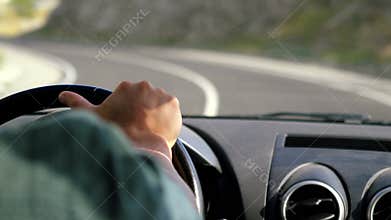 Man`s hand on the steering wheel driving a car in the long road along mountains in slow motion. 3840x2160