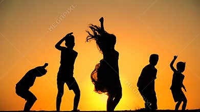 Silhouette of five kids jumping against sunset