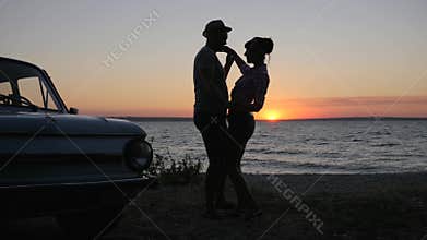 Loving couple dancing on river`s shore in sunset, Trip of Lovers on seafront, dance young couple to Embankment sea