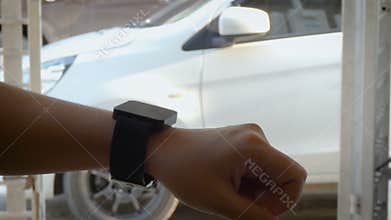 Hands of woman using smart watch to open and close lock and unlock the door of car metaphor remote security application concept